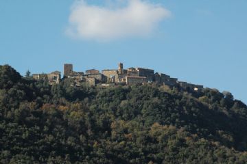 Vista da levante. Emergono la torre primo - rinascimentale, a sinistra, e il campanile datato 1788, a destra. Si noti la conformazione arcuata dell'abitato, che segue lo sperone roccioso sul quale è stato edificato a partire dalle primissime fasi della storia del castello (secolo XII).<br>Questa immagine è del tutto simile ad una carta settecentesca, in possesso di privati , dalla quale emerge quasi esattamente la medesima situazione architettonica ad eccezione dell'altezza del torrione, più alto di circa 6 metri, e della porzione di case alla sua sinistra. 